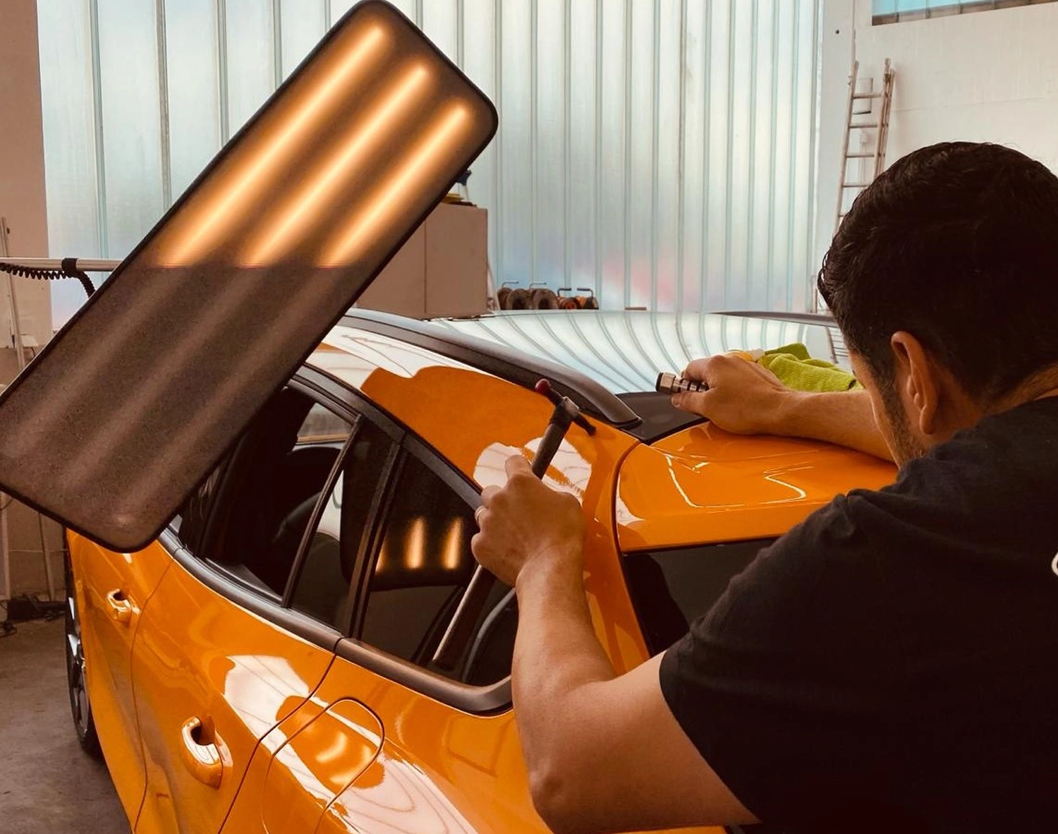 Mann repariert Auto von Hagelreparatur24 GmbH